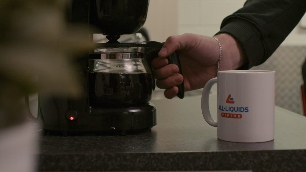 All Liquids Piping B.V. logo on a coffee mug, part of a PuraVideos brand film showcasing expertise in piping systems, industrial hoses and temporary installations